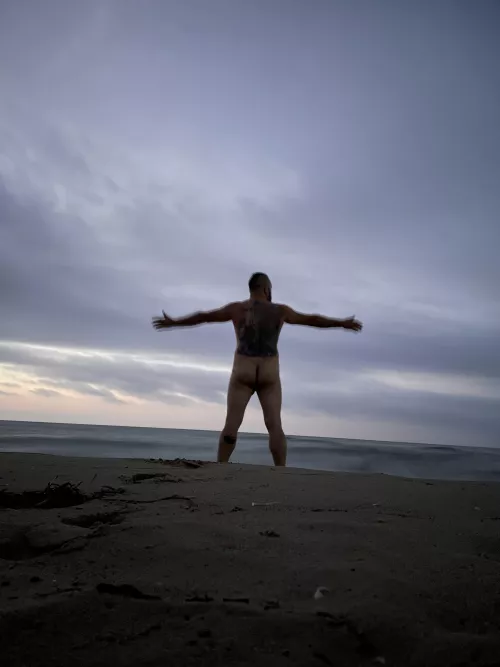 Bad inked and naked man at the beach.