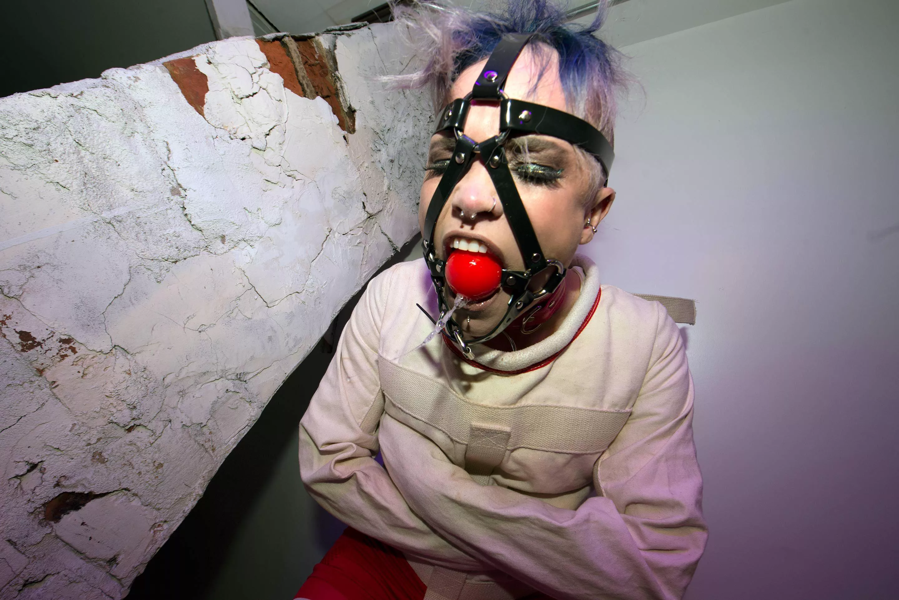 Drooling from her call gag while in a straight jacket