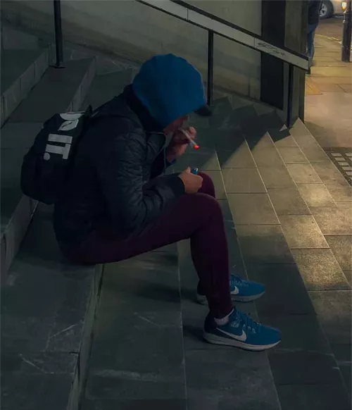 Scally lad having a smoke on some steps in Soho