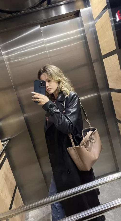 In the elevator with a black coat.
