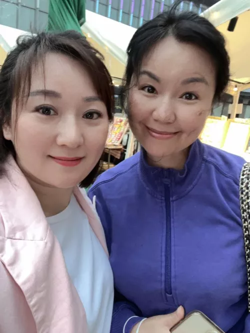 Tall, thin, busty MILF with confident smile vs younger lady with forced smile.