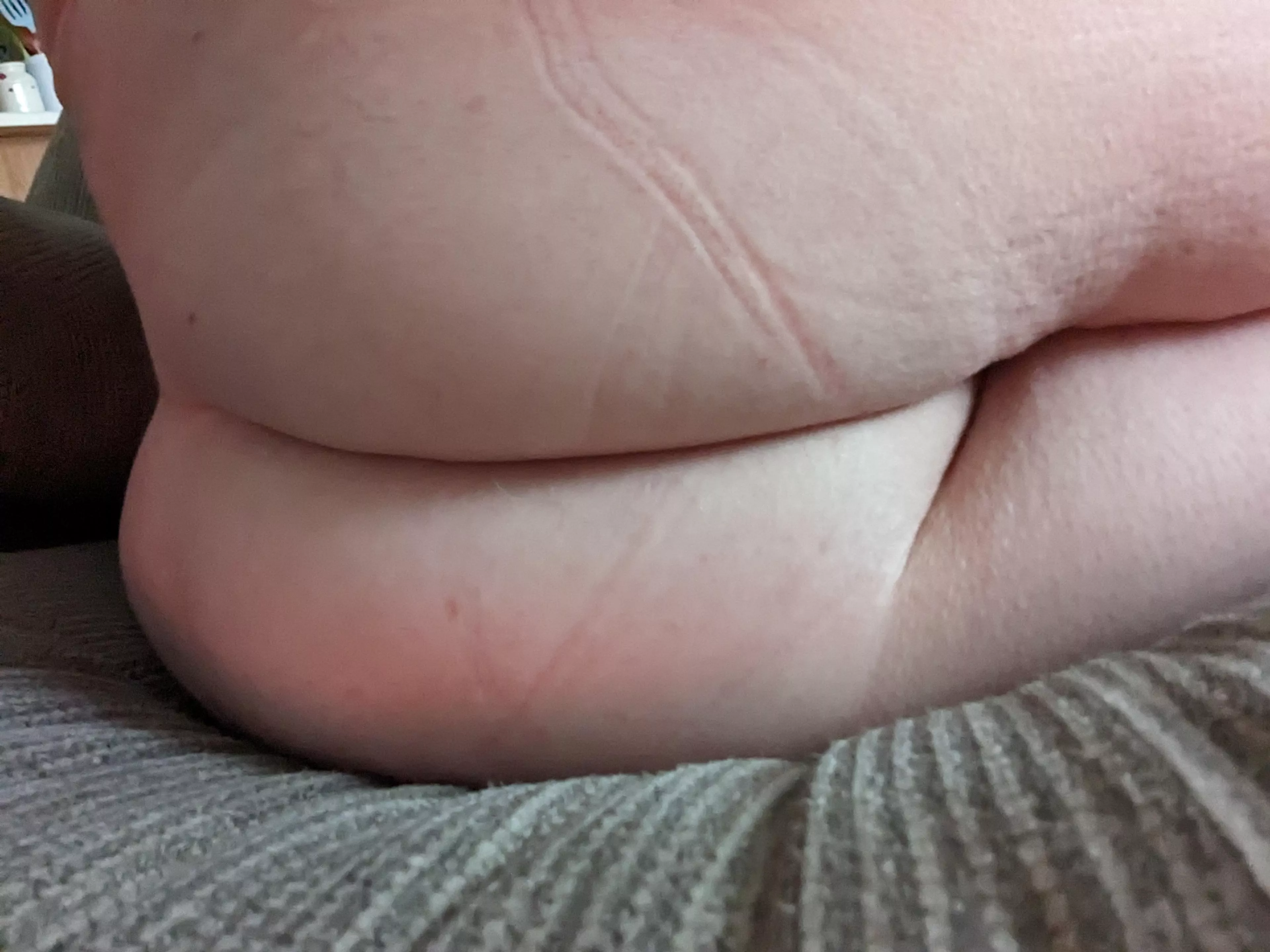 Sitting on the couch ass naked.