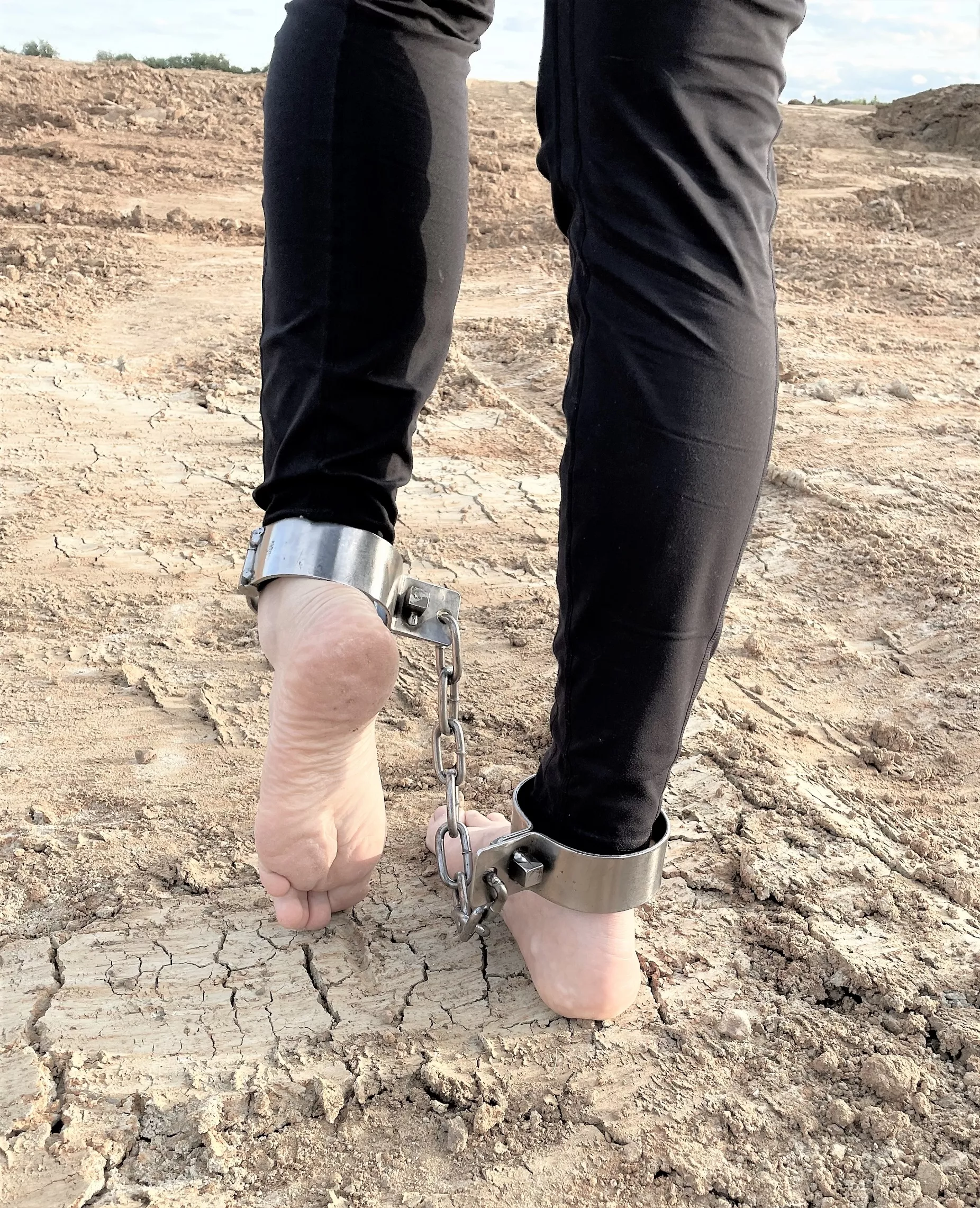 Shackled barefoot on dirt