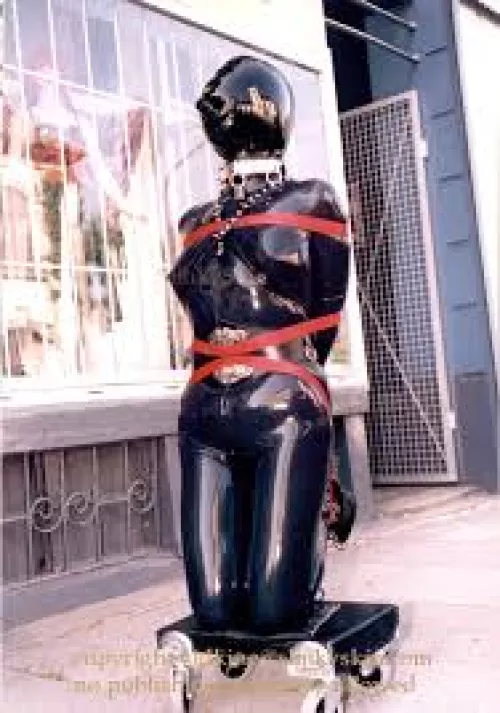 Does anyone have the link to a video similar to the image? It is of a person getting rolled out of a building in bondage for public display,