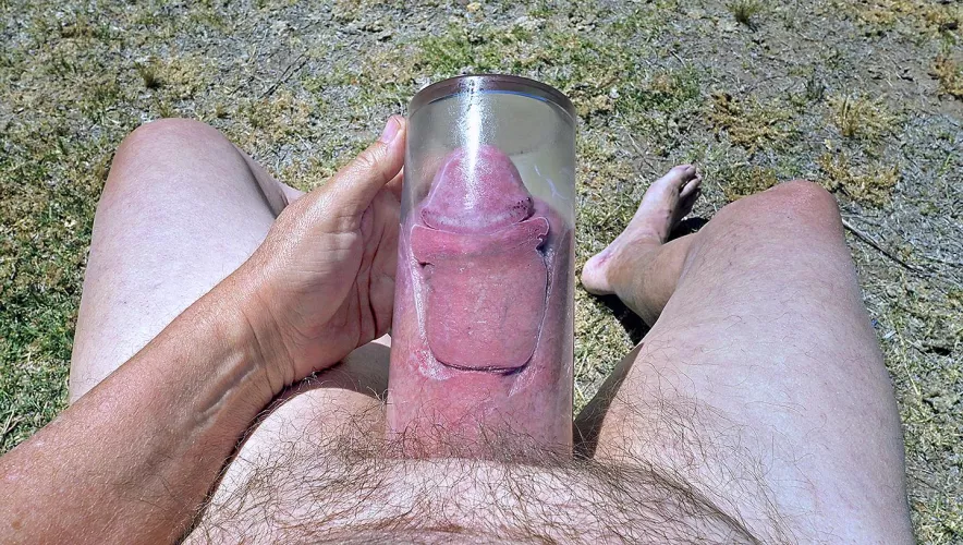 Holding my pumped cock in glass vase outdoors in my backyard.
