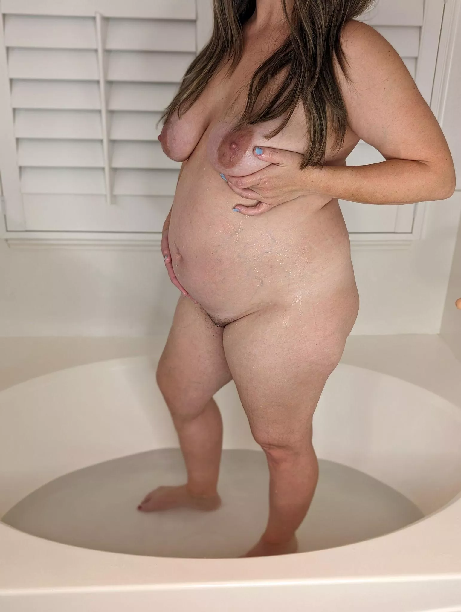 Dive in and join this sexy pregnant milf for some steamy tub time