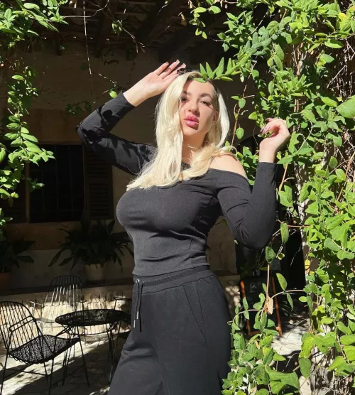 Blonde in black near a bush 