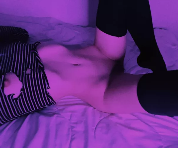 The purple light and tattered sweatshirt highlight the curves of my body