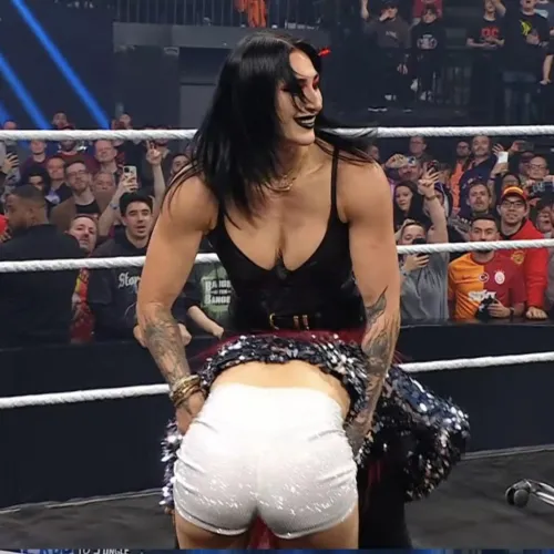 Rhea Ripley about to power bomb Iyo Sky onto Bianca Belair on a table