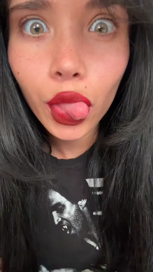 Wide-eyed, tongue out, lipstick loud.