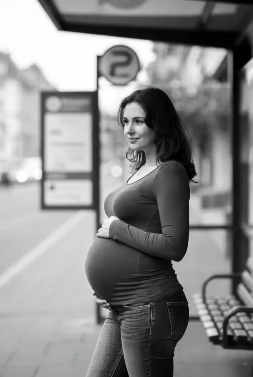 Pretty pregnant woman waiting for the bus